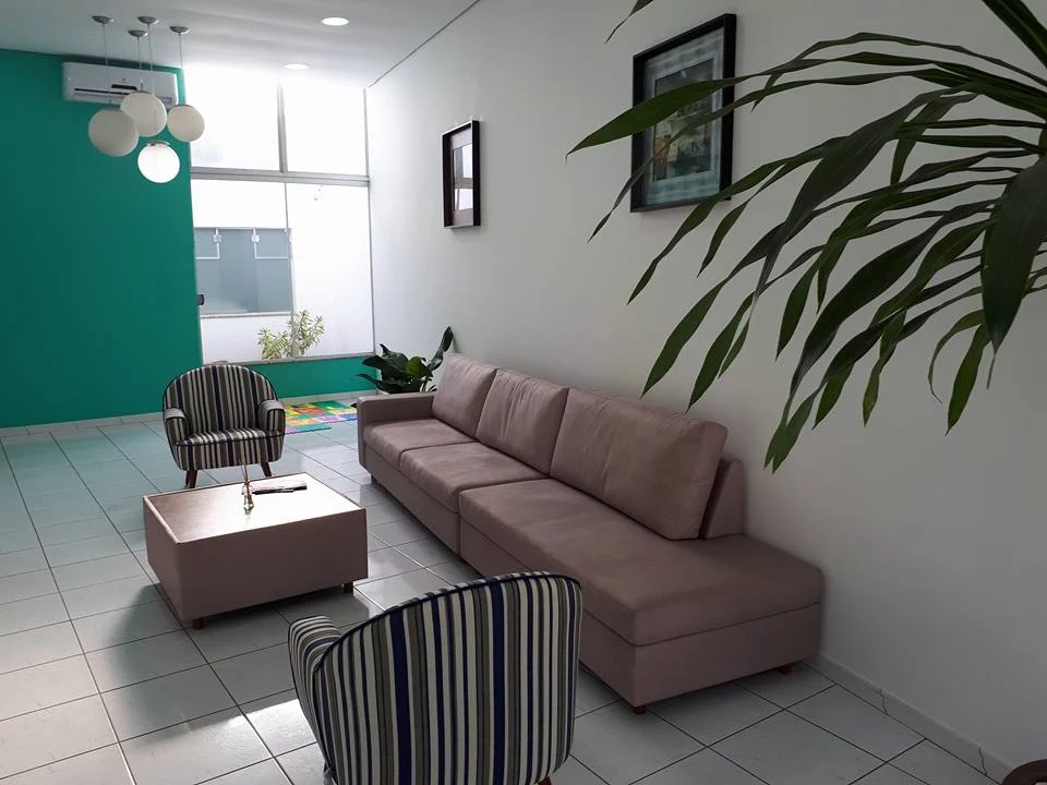 Sala de espera da Odonto Pratti, com parede verde-água, poltronas listradas e sofá